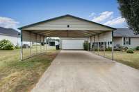 Front of house- concrete driveway & sidewalk, two car attached garage with single rollup door, two car carport