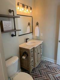 This updated bathroom has adorable lighting, cabinet & flooring.