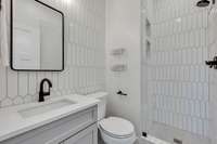 Shared hall bath with floor to ceiling designer tile.