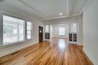 View from living room into study showcasing built-in cabinets and ceiling beams, typical in homes of this era & architechtural style.