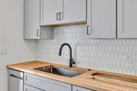 Stylish tile backsplash, gooseneck faucet and butcher block countertops.