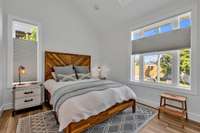 Bedroom  with vaulted ceilings, large windows and pristine floors.