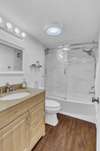 Pretty bath with newer vanity, lighting, flooring, commode and a gorgeous tub/shower enclosure.