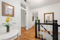 Moving from the kitchen to the primary bedroom on the main level, you will notice the historic charm continues with the transom windows, ceiling height, and staircase.