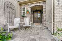 Limestone front porch with arched steel Tuscany style doors.