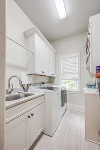 Laundry with sink, cabinets, drying rod - opposite folding countertop with shelves above