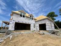 View of 3 car garage and pedestrian door. *this home is under construction  Photo Taken 8/14/24