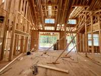 Great Room with vaulted ceiling,  slider doors, wood-burning fireplace, built-ins on each side of the fireplace. *this home is under construction  Photo Taken 8/14/24