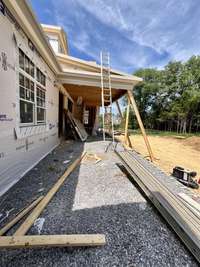 View of Grilling porch and covered living porch with wood-burning fireplace. *this home is under construction  Photo Taken 8/14/24