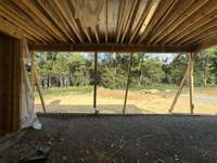 View from Great Room looking onto Covered Porch with Wood-burning Fireplace.  *this home is under construction  Photo Taken 8/15/24