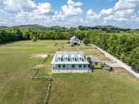 Rare Williamson Co 11.21 acre farm with a single level home, wrap around porch, bardominium, 8 stall barn, and fenced and cross fenced pastures.