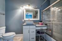 Bathroom with decorative basin, counters, and shower/tub with glass sliding doors.