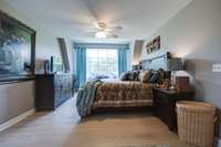 Barndominium bedroom with lots of light shinning in and a lighted ceiling fan.