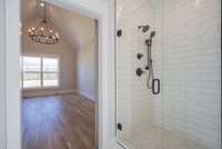 Beautiful Shower with handheld sprayer in shower, black plumbing, and frameless door.