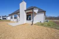 Rear view of home with covered porch, wood burner fireplace and patio