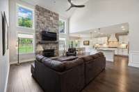 The 2-story Family Room showcases a stone fireplace with wooden mantel flanked by windows.