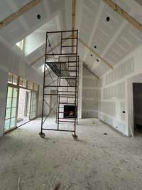 Great Rood with vaulted ceiling,  wood-burning fireplace with stone chase and arccustone mantle and built-ins on the right side of fireplace.  *this home is under construction. Photo taken: 8/9/24