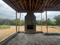 Covered outdoor living featuring a 42" wood-burning, plus an adjoining grilling porch and grade level patio.  *this home is under construction. Photo taken: 8/14/24