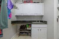 The laundry room has extra cabinetry, a sink m and a granite topped folding counter.