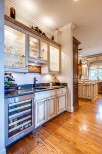 Fully equipped wine bar with copper sink, wine cooler, beautiful custom cabinets with lighted shelves