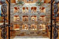 Step into the custom designed Italian style wine cellar featuring exquisite hand-carved lighted wine cubbies, elegant granite wine bars and custom iron gates