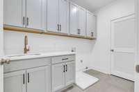 Large laundry room with lots of cabinets and a utility sink and folding counter!