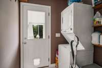 Laundry room with shelving and washer and dryer that stay with the home.