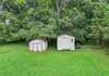 Great backyard surrounded by mature trees and two sheds.