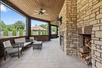 wood burning fireplace is at the center of screened in porch area