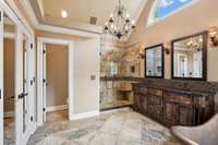 Primary bath features elegant chandelier, double vanity, and exquisite sconce lighting.