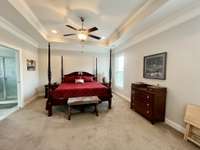 Primary suite on main level with trey ceiling recessed lighting and ceiling fan over looking the screened backporch. Carpet flooring; Large bath suite with walk in closet