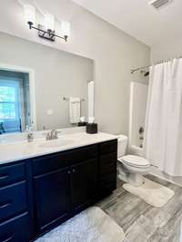 Guest bath has LVT flooring with 6 ft vanity with tub/shower combo