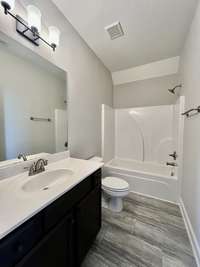 Upstairs bath room with tub/shower combo with single vanity; LVT flooring