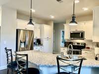 Recessed lighting in Kitchen with pendants over the granite bar top eating area.