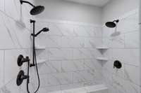 large tiled shower with 2 shower heads and a bench