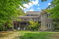 This view of the back side of the home shows the two levels of outdoor entertaining. The "tower" on the right includes the primary bedroom suite.