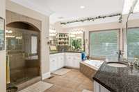 The bathroom in the primary suite has two separate custom-built vanities, a shower and a separate  tub.