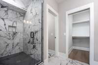 Italian Tile Shower Surround with Bronze accent Shower head accessories, separate private Toilet and Walk-In closet. Built-in nook for bathroom essentials.