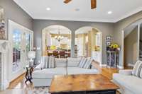 Open to the Kitchen, the Family Room showcases a gas fireplace with glass tile surround, crown molding, recessed lighting, built-in speakers, ceiling fan, and access to the Covered Deck through a glass door.