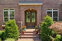 Welcome home! Lush landscaping sets the stage for this charming open porch and covered entry where you can sip on your favorite beverage and watch the neighborhood stroll by.