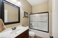 This Full Bath features tile flooring, vanity with storage, framed mirror, and a tub/shower combo with glass sliding door.