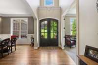 This spacious 2-story Foyer leaves a lasting first impression with extensive hardwood flooring (throughout the most of the main living areas of the home), black metal chandelier, plant shelf  with window, and coat closet.