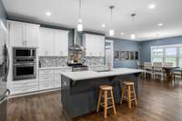 Double ovens, bar seating and a spacious table area looking toward the back yard.