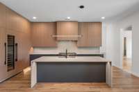 Sleek, modern cabinetry in the kitchen featuring wood tones and durable acrylic rather than painted cabinets