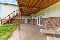 Stamped concrete patio below the covered top deck.  So relaxing and private. Double doors lead into the huge basement area.