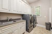 The laundry room is located just off the garage and mudroom. Extensive cabinetry and a built in ironing board are highlights.