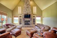 Stunning stone fireplace is the centerpiece of the Family room that flows with the Kitchen area, and is flanked by tall cabinets which houses Audio equipment. Blinds above operate remotely. A peaceful view from all windows can be enjoyed.