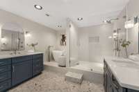 The primary bath adds a touch of whimsy with slate-flecked terrazzo floors, an elevated soaking tub, twin vanities, and an airy shower.