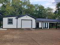 Storage building with three carport spaces also includes a 1 car garage, full bath & gathering area