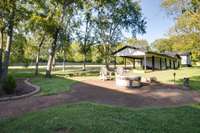 Carport, storage building, & lots of parking spaces seen behind the firepit